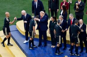 FIFA World Cup 2026 - Final - Spain v Argentina - عروبة الاخباري | Oroba News A suited man hands a medal to a player on a blue and yellow podium during a formal sports award ceremony with teammates and officials around them