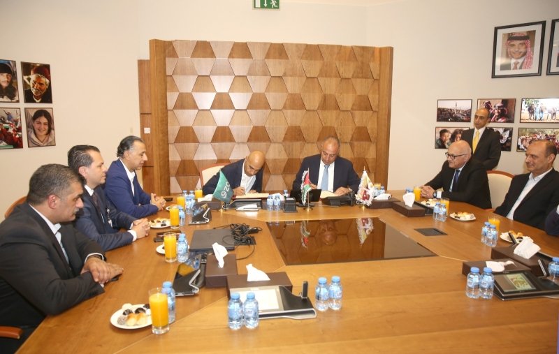 6a4e39dfb6fee - عروبة الاخباري | Oroba News Two men sign documents at the center of a large wooden conference table while colleagues look on in a formal boardroom.
