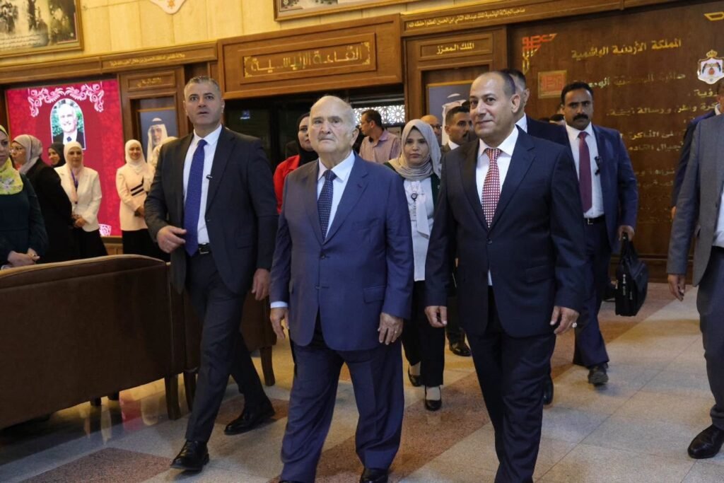 Group of formally dressed officials walking through a wood-paneled government lobby with onlookers in the background.