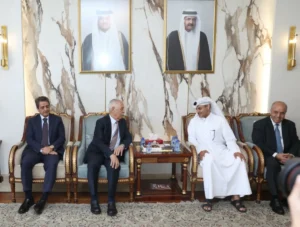 755366 - عروبة الاخباري | Oroba News Four men sit in a formal room on ornate chairs, with a marble wall and portraits behind them, chatting around a small table with water bottles and tissues nearby.