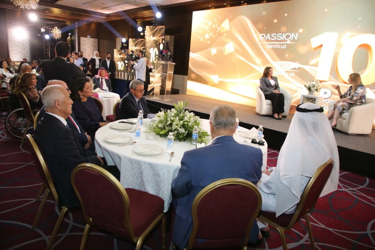756668 Formal gala with round tables and guests in suits watching a panel on stage; large screen displays 'PASSION drives us'.