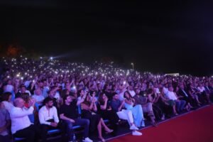 WhatsApp Image 2026-07-17 at 121755 PM - عروبة الاخباري | Oroba News Large outdoor concert crowd at night, many people holding up illuminated phone screens creating a sea of lights. (Informative, concise)