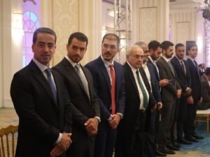 WhatsApp Image 2026-07-18 at 112234 AM 5 - عروبة الاخباري | Oroba News Group of men in dark suits standing in a line at a formal event in an ornate room.