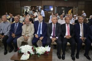 WhatsApp Image 2026-07-23 at 42558 PM - عروبة الاخباري | Oroba News Group of men in suits seated in a formal event, with a floral centerpiece on the table in front.