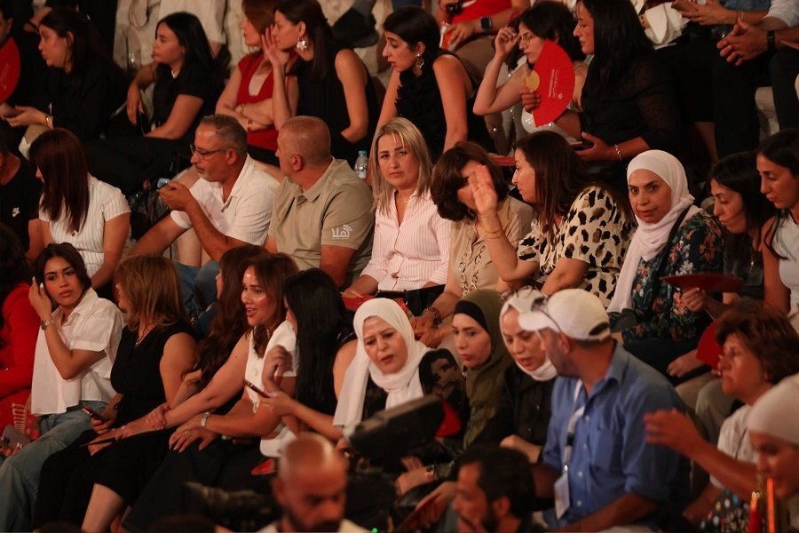 00000000000996727_2107029120025874_2160197415418076468_n Crowded audience at an indoor event; diverse group of adults, including women in headscarves, watching attentively.