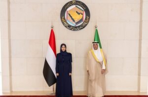 1700935 - عروبة الاخباري | Oroba News Two officials stand side by side in front of a government emblem, flanked by a red-white-black Yemeni flag and a green flag.