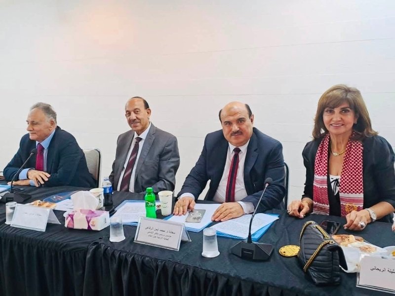 6a74778bc774e - عروبة الاخباري | Oroba News Four professionals seated at a conference table with papers, microphones, and drinks in a formal meeting setting.