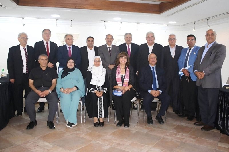 6a74778c4a913 - عروبة الاخباري | Oroba News Group of adults in business attire posing for a formal group photo in a conference room, with some seated in front and others standing behind them.