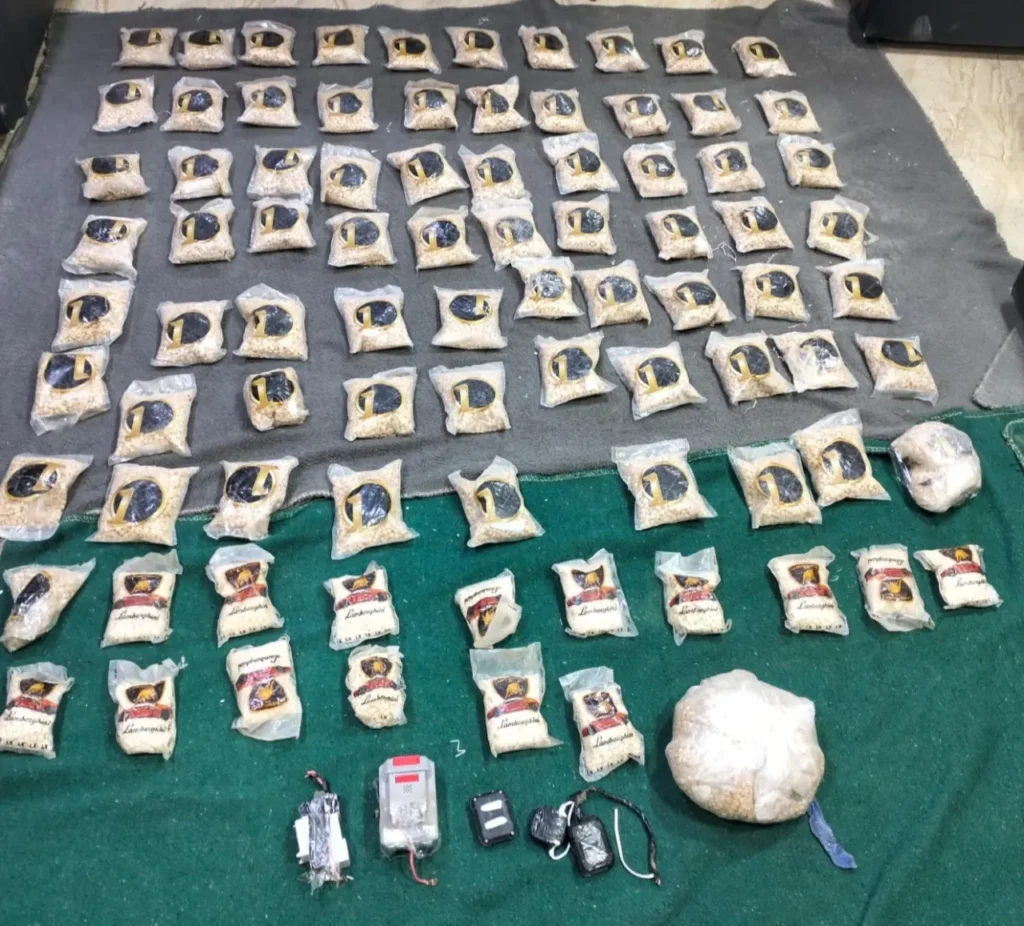 6a796f3ced080 - عروبة الاخباري | Oroba News Numerous small bags containing a white powdery substance arranged in rows on gray and green mats, with a large bag and assorted devices at the bottom.