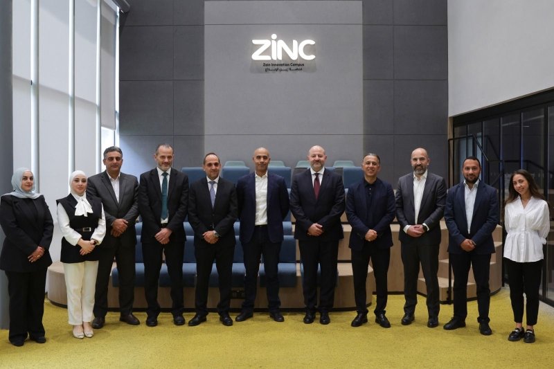 6a95232f19883 - عروبة الاخباري | Oroba News Group of twelve professionals in business attire posing for a photo in a modern conference room with a gray wall and a prominent ZiNC sign above them.