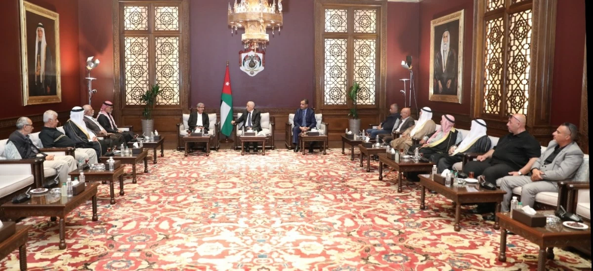 760737 - عروبة الاخباري | Oroba News Formal meeting in a grand room with the Jordan flag, portraits, and officials seated around low tables forming a U-shape.