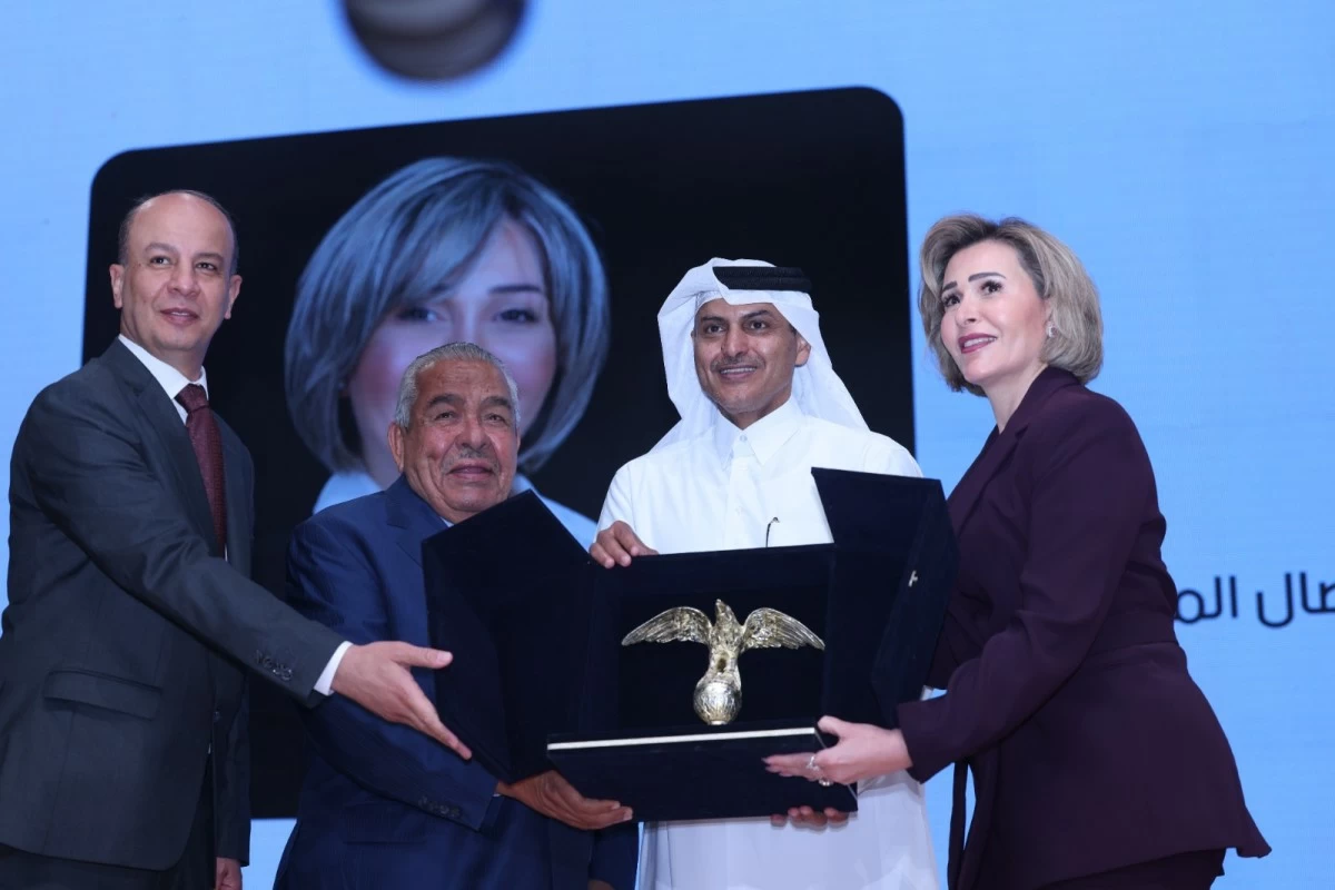 760766 - عروبة الاخباري | Oroba News Four dignitaries on a stage present a black box containing a gold eagle award to a woman in a burgundy suit.