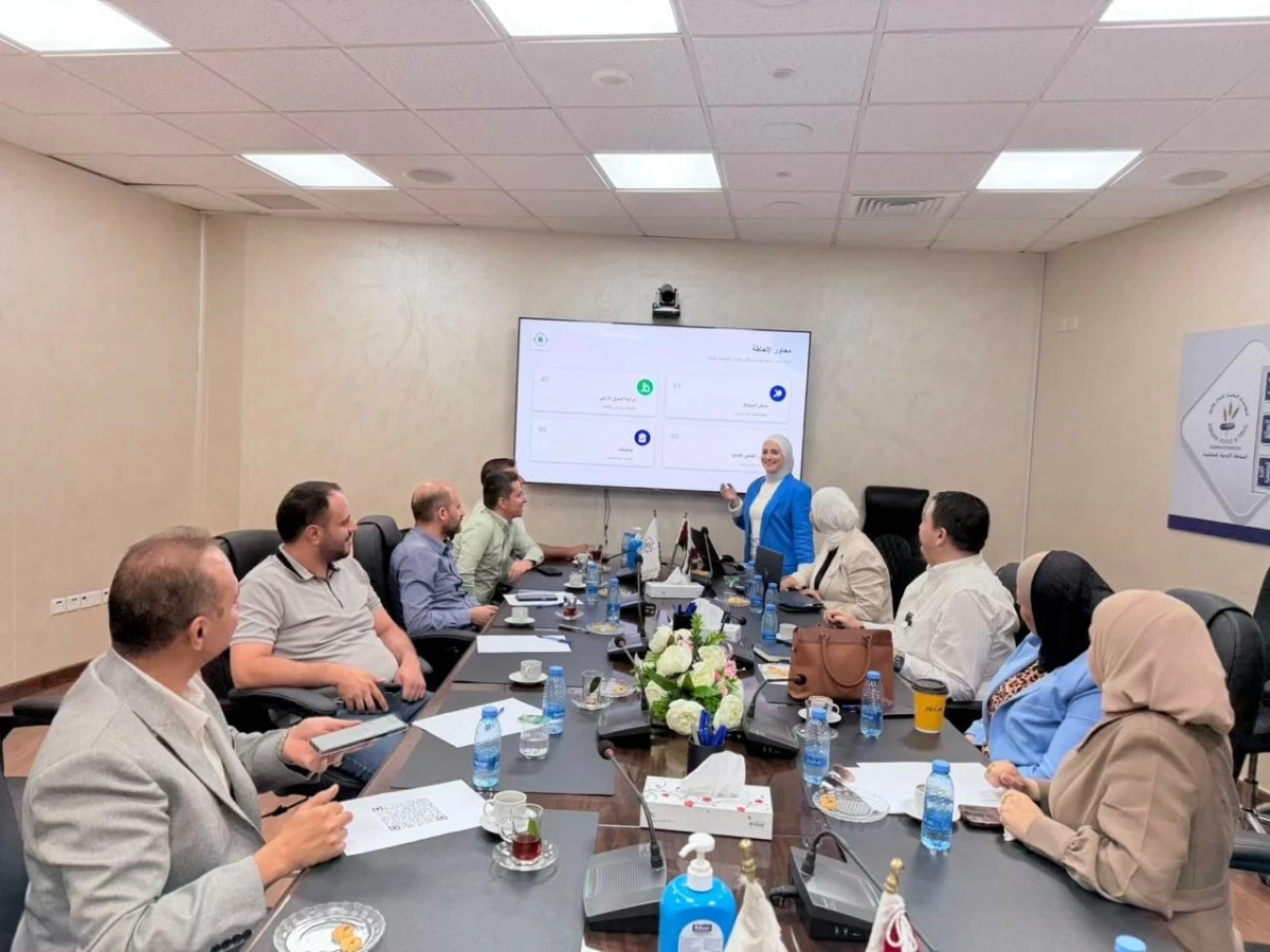 764234 - عروبة الاخباري | Oroba News Group of professionals in a conference room; a woman in blue presents at a large screen.