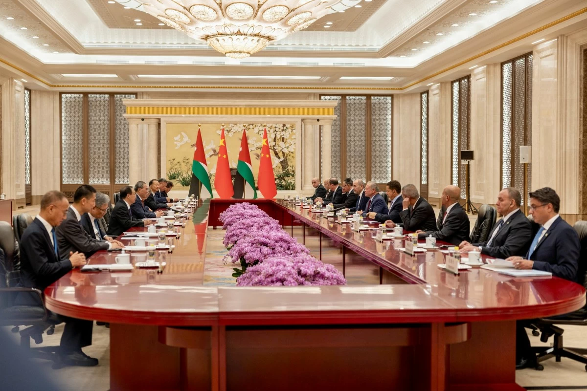 764901 - عروبة الاخباري | Oroba News Diplomatic meeting in an ornate chamber with delegates seated along a long red table, pink flowers down the center, and Palestinian and Chinese flags behind the head of the table.