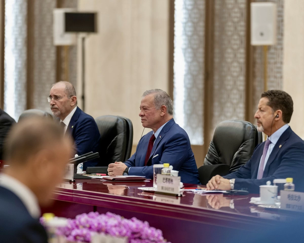 764902 - عروبة الاخباري | Oroba News Three men in suits seated at a polished conference table during a formal meeting, with microphones and nameplates nearby.