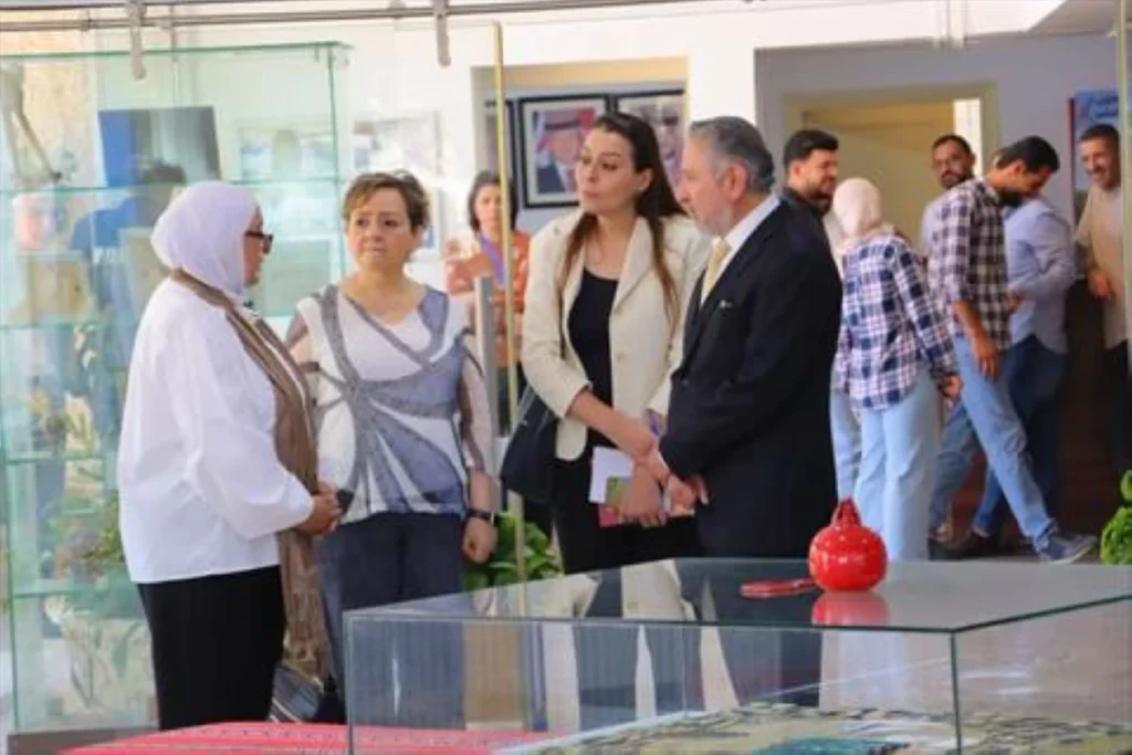 Group of adults in a gallery or showroom looking at a display case and chatting nearby.