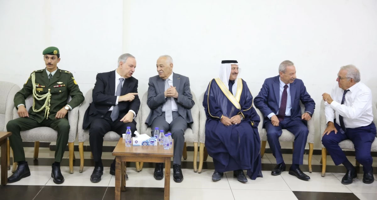 765041 - عروبة الاخباري | Oroba News Six men sit on beige couches along a wall, including a military officer in green uniform and a man in traditional robe, chatting in a formal setting.