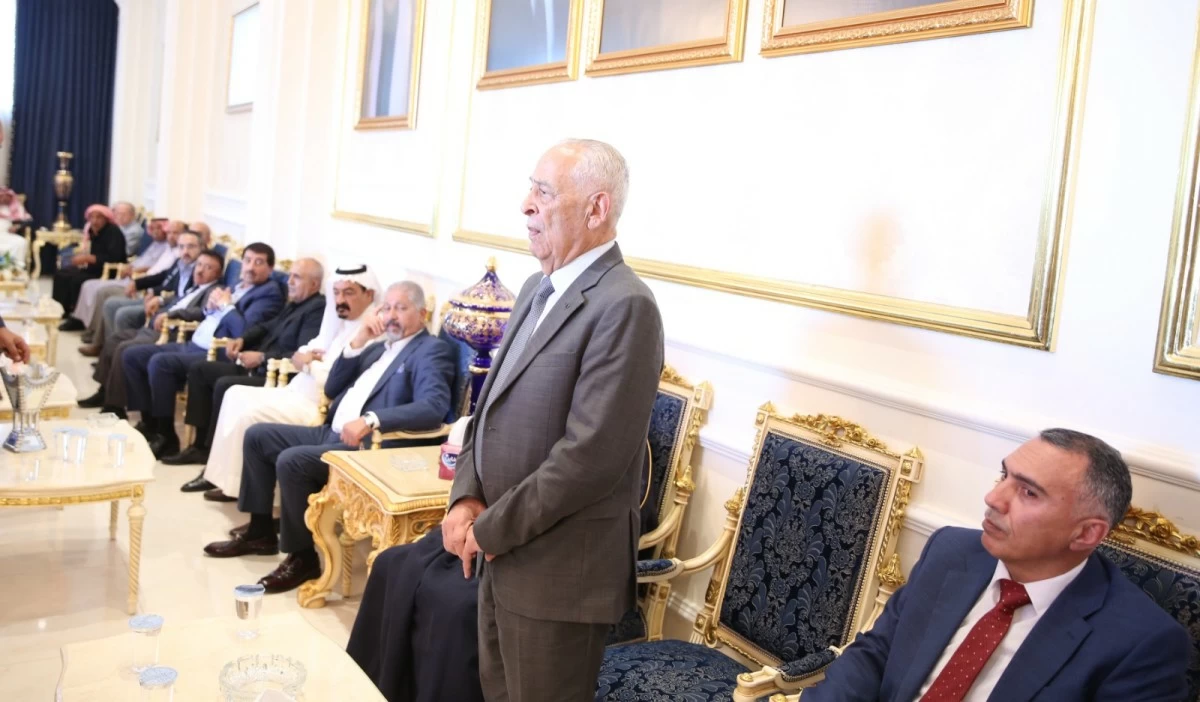 765513 - عروبة الاخباري | Oroba News Senior man in a gray suit stands in an opulent room as officials in suits sit along gold-trimmed chairs.