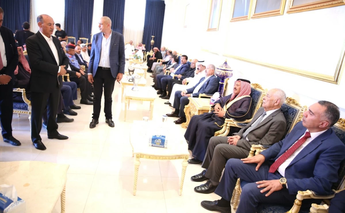 765515 - عروبة الاخباري | Oroba News Two men in suits talk near a row of seated guests in a formal, ornate room with gold-trimmed chairs.