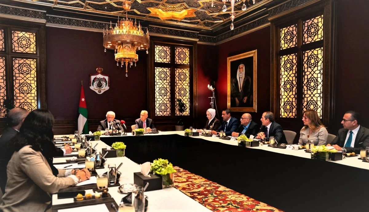 765698 - عروبة الاخباري | Oroba News Diplomatic meeting in a lavish room with a U-shaped table, officials in suits seated with Jordan flag in the background and a chandelier above.