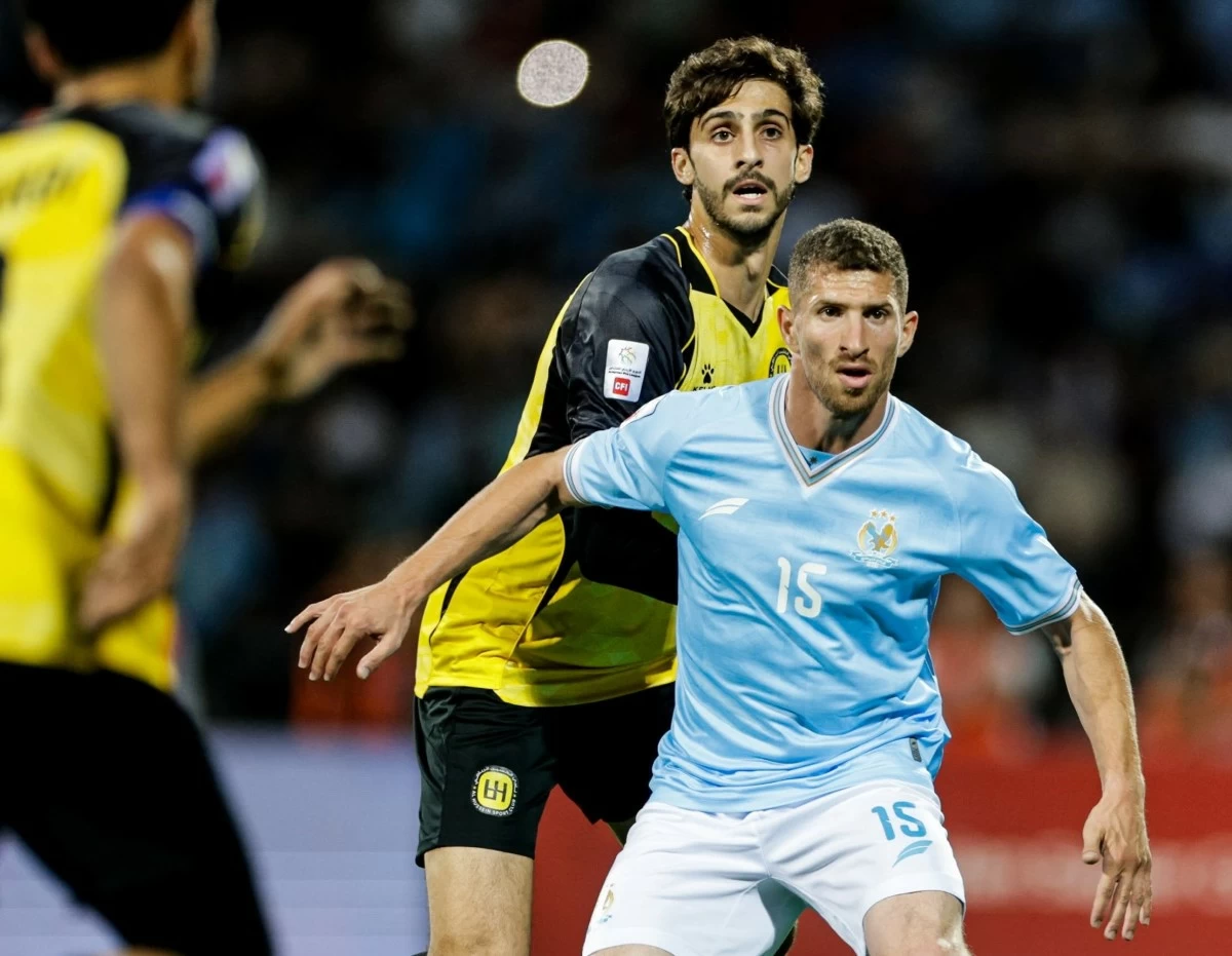 765907 - عروبة الاخباري | Oroba News Soccer players in action: a light-blue jersey player (#15) challenges for the ball while a yellow-and-black defender closes in from behind.