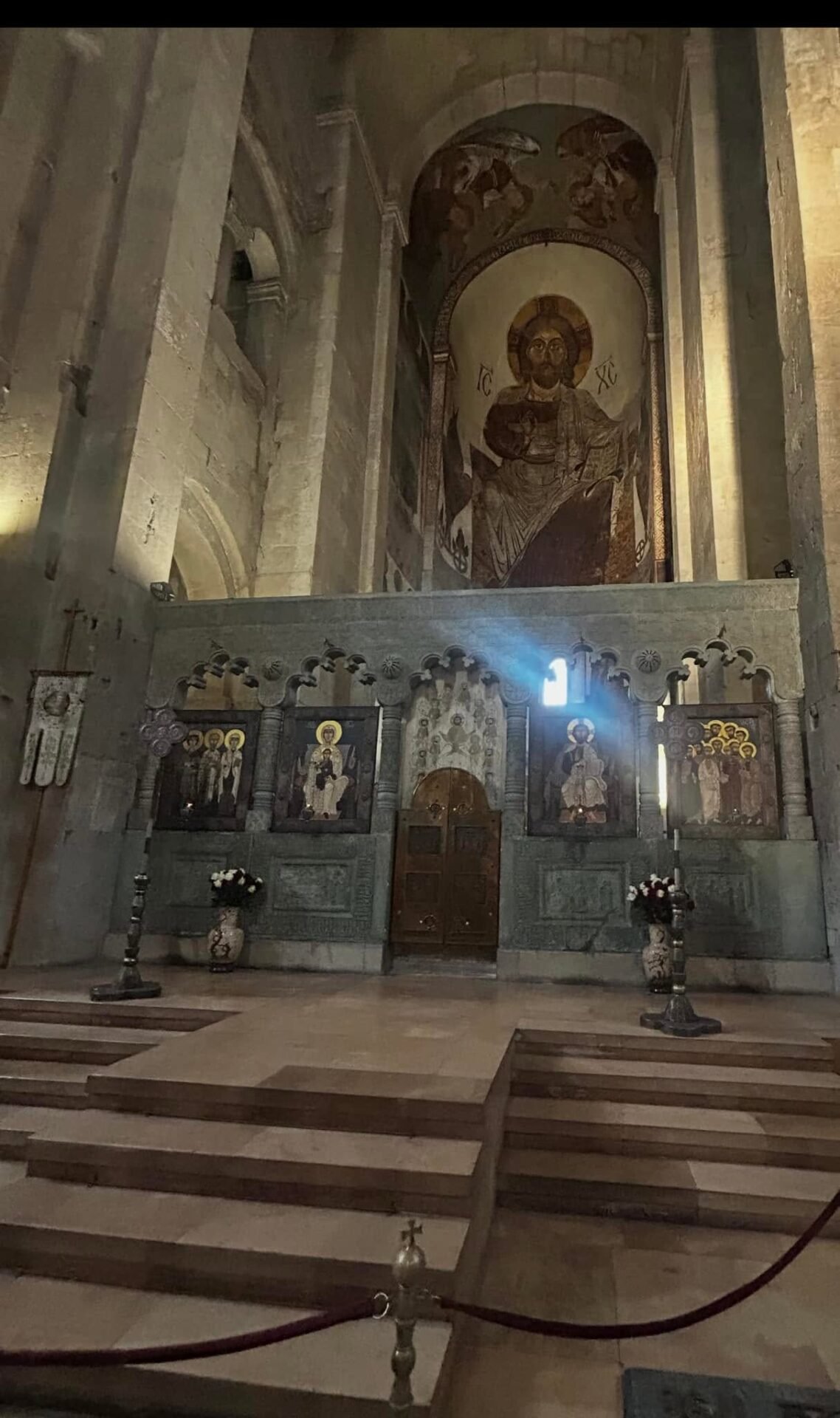 Screenshot - عروبة الاخباري | Oroba News Interior of a historic church with an ornate iconostasis featuring multiple icons and a large central mosaic of Christ above the altar