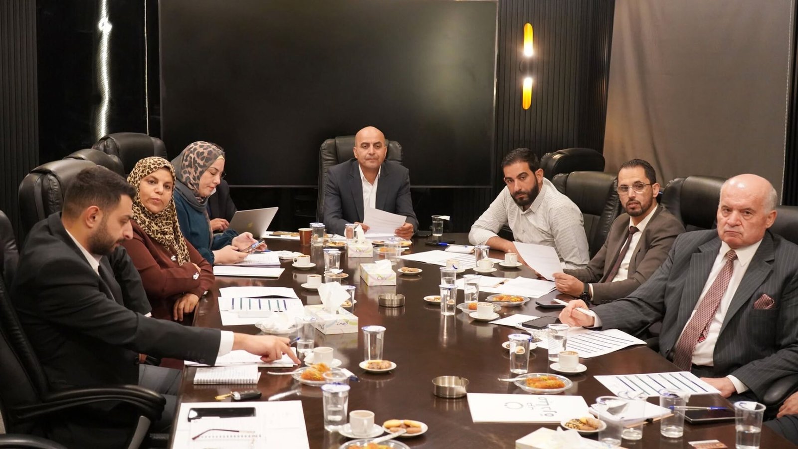 775858171_122145932709082282_2279275090813162192_n - عروبة الاخباري | Oroba News Diverse group of professionals around a large conference table reviewing documents and discussing during a meeting.