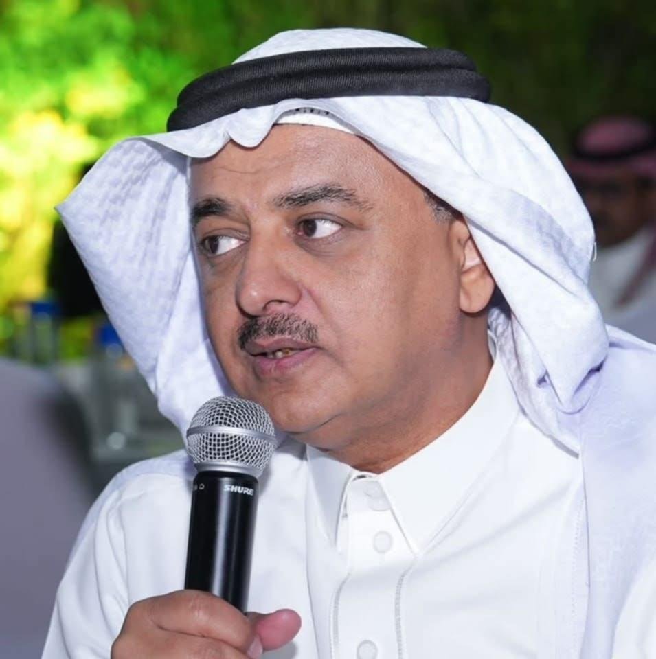 789005e22aa-2c34-427e-b49b-2026 - عروبة الاخباري | Oroba News Man in a white thobe and headscarf speaks into a microphone at an outdoor event, looking to his left.