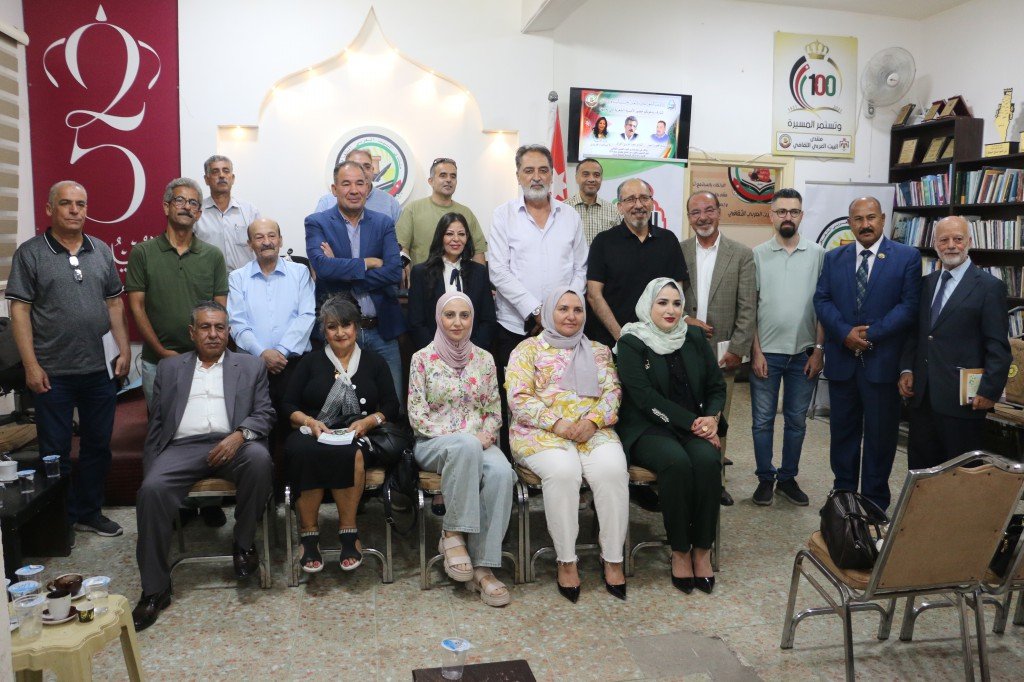 WhatsApp Image 2026-08-04 at 111739 AM Group portrait of men and women in a community center; banners and shelves with books visible in the background.