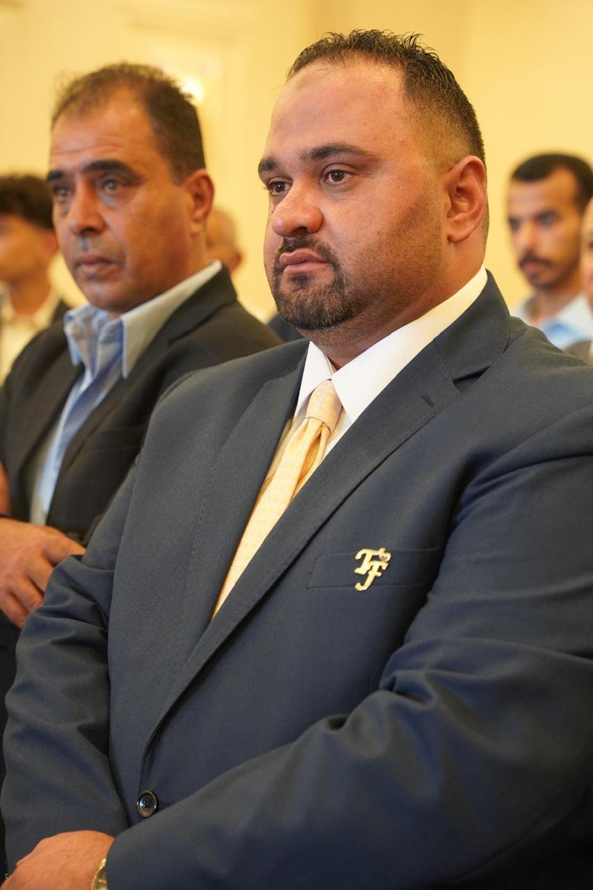WhatsApp Image 2026-08-05 at 32452 PM6 - عروبة الاخباري | Oroba News Man in a dark suit and yellow tie at a formal event, with a focused expression.
