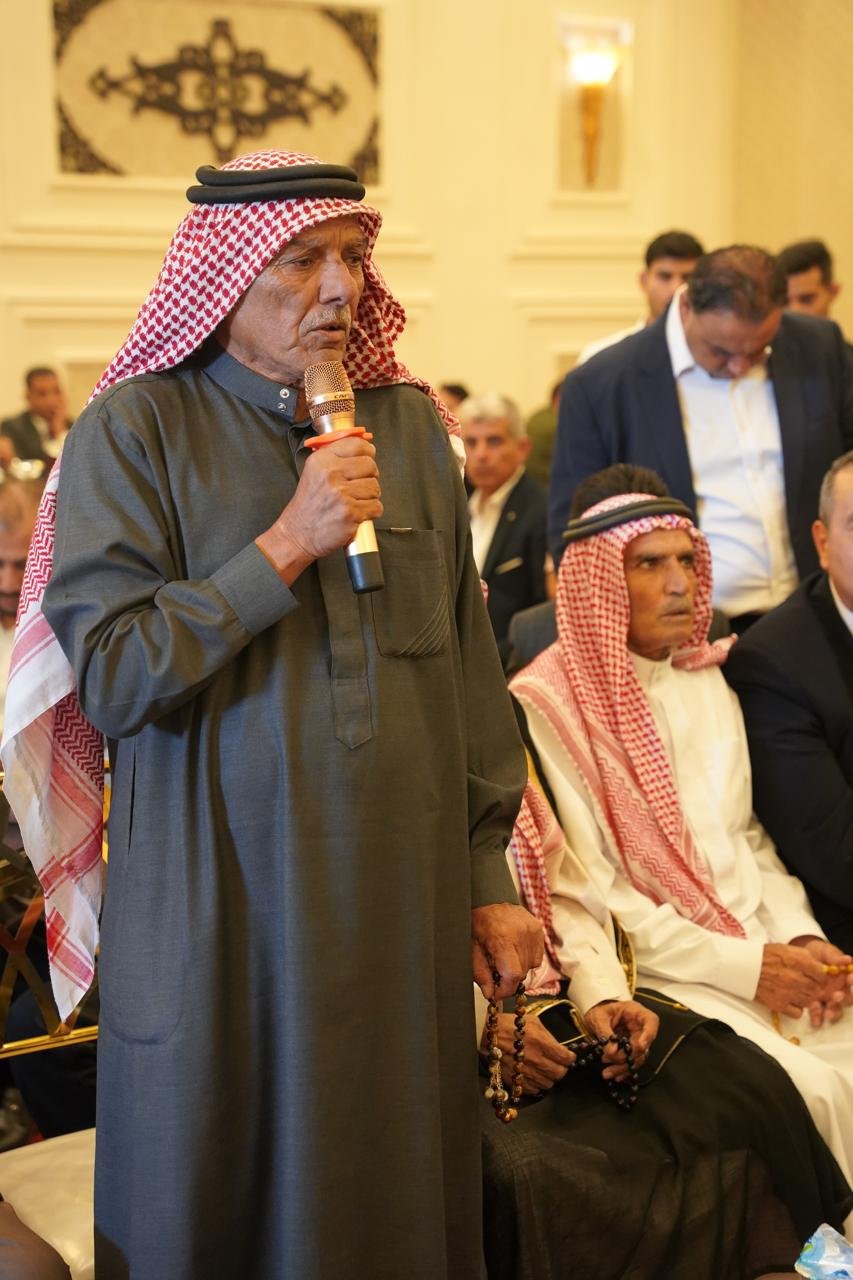 WhatsApp Image 2026-08-05 at 32453 PM1 - عروبة الاخباري | Oroba News Elderly man in traditional attire speaks into a microphone at a formal gathering.