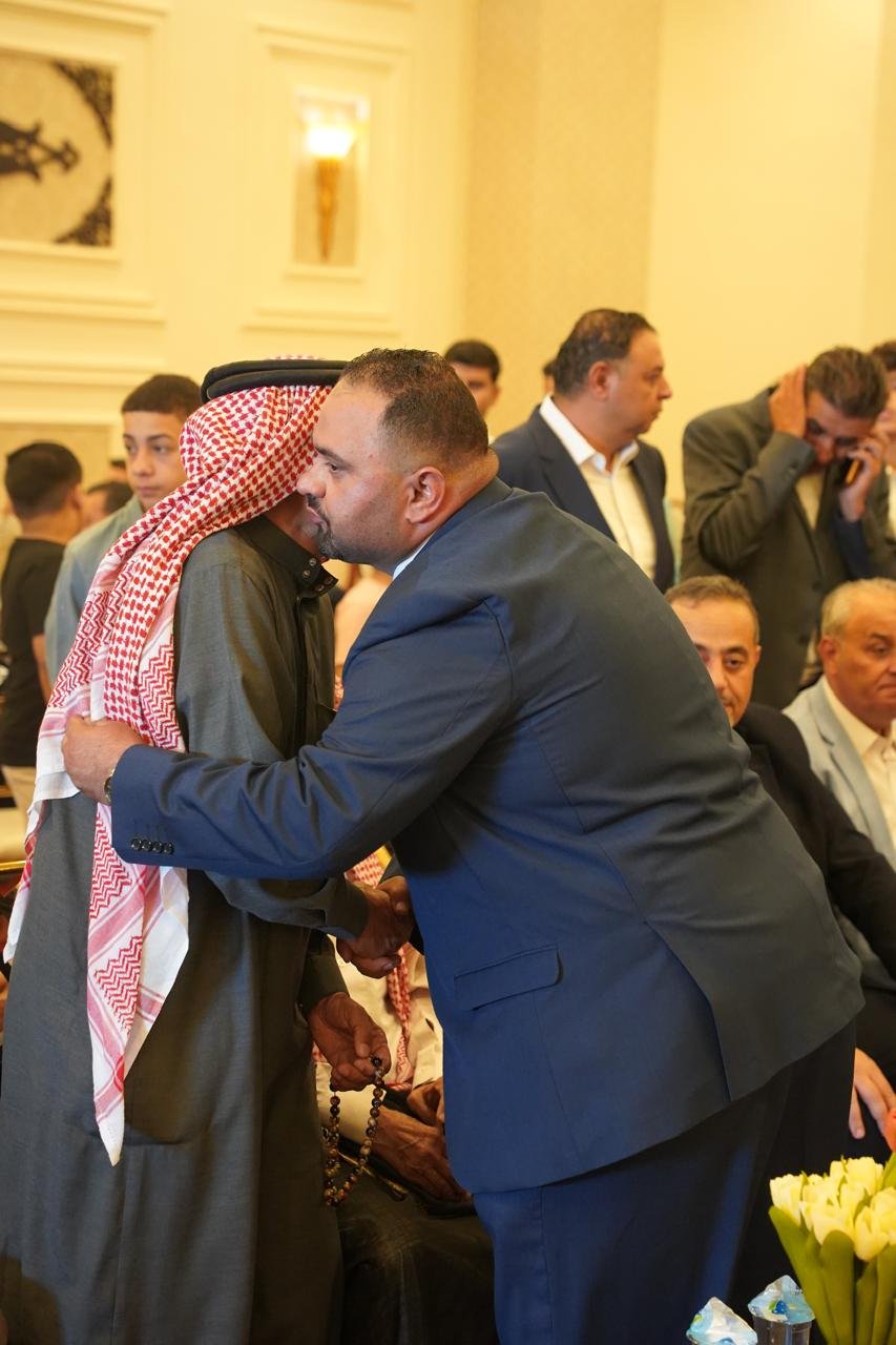 WhatsApp Image 2026-08-05 at 32453 PM3 - عروبة الاخباري | Oroba News Two men greet with a warm hug at a formal event: one in a dark suit, the other in a traditional keffiyeh and long robe, handheld beads in view behind them.