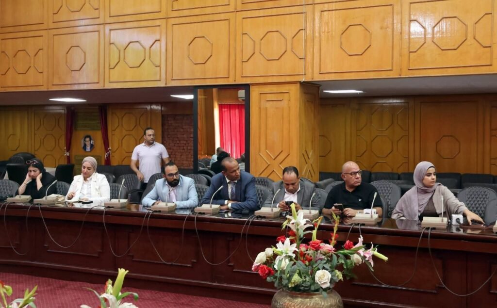 WhatsApp Image 2026-08-06 at 63456 PM2 - عروبة الاخباري | Oroba News Panel of people seated along a long conference table with microphones in a wood-paneled meeting room.