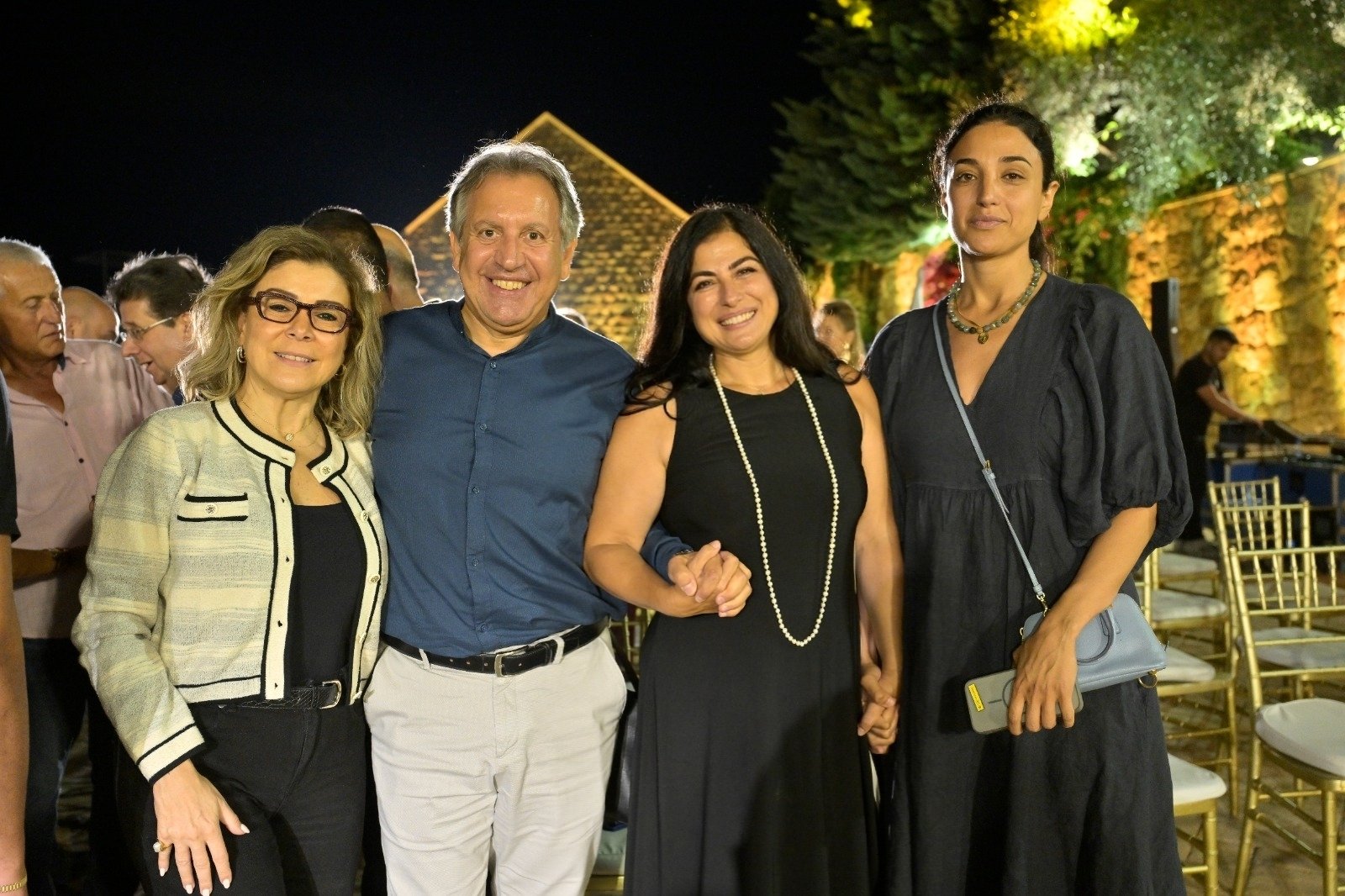 WhatsApp Image 2026-08-07 at 14943 PM 4 - عروبة الاخباري | Oroba News Group of four adults smiling at an outdoor night event, posing arm-in-arm in front of a decorated venue.",