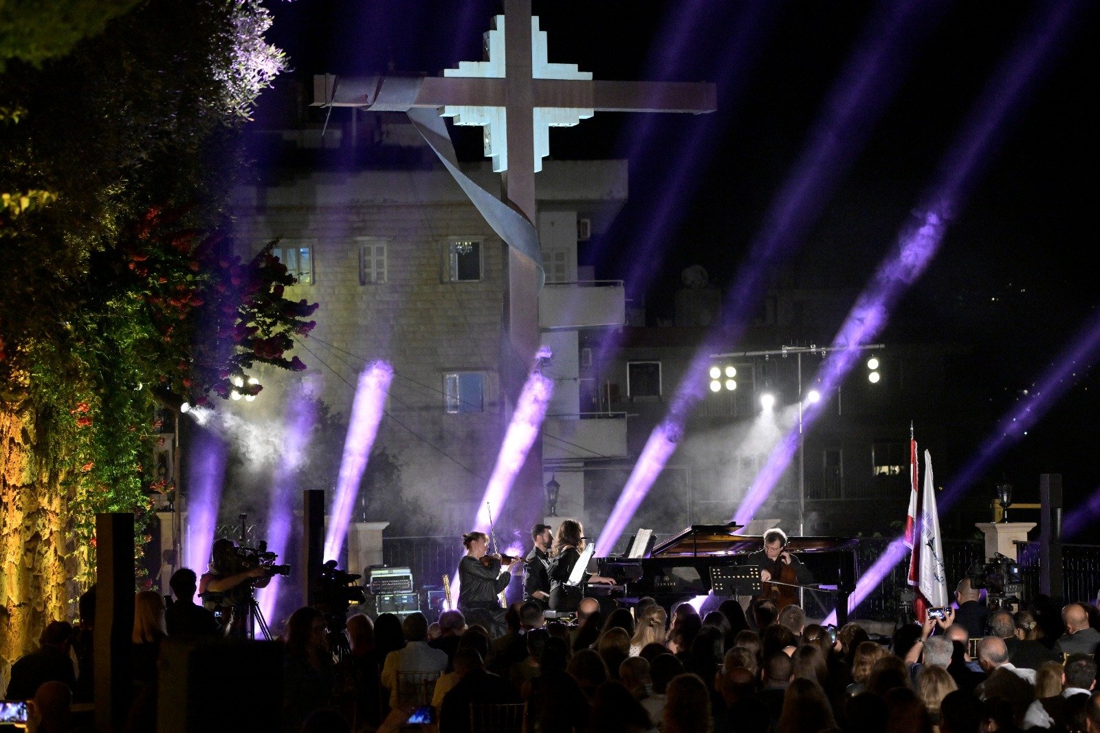 WhatsApp Image 2026-08-07 at 14947 PM 3 - عروبة الاخباري | Oroba News Nighttime outdoor concert with a large illuminated cross sculpture in the background and purple stage lights sweeping the crowd.
