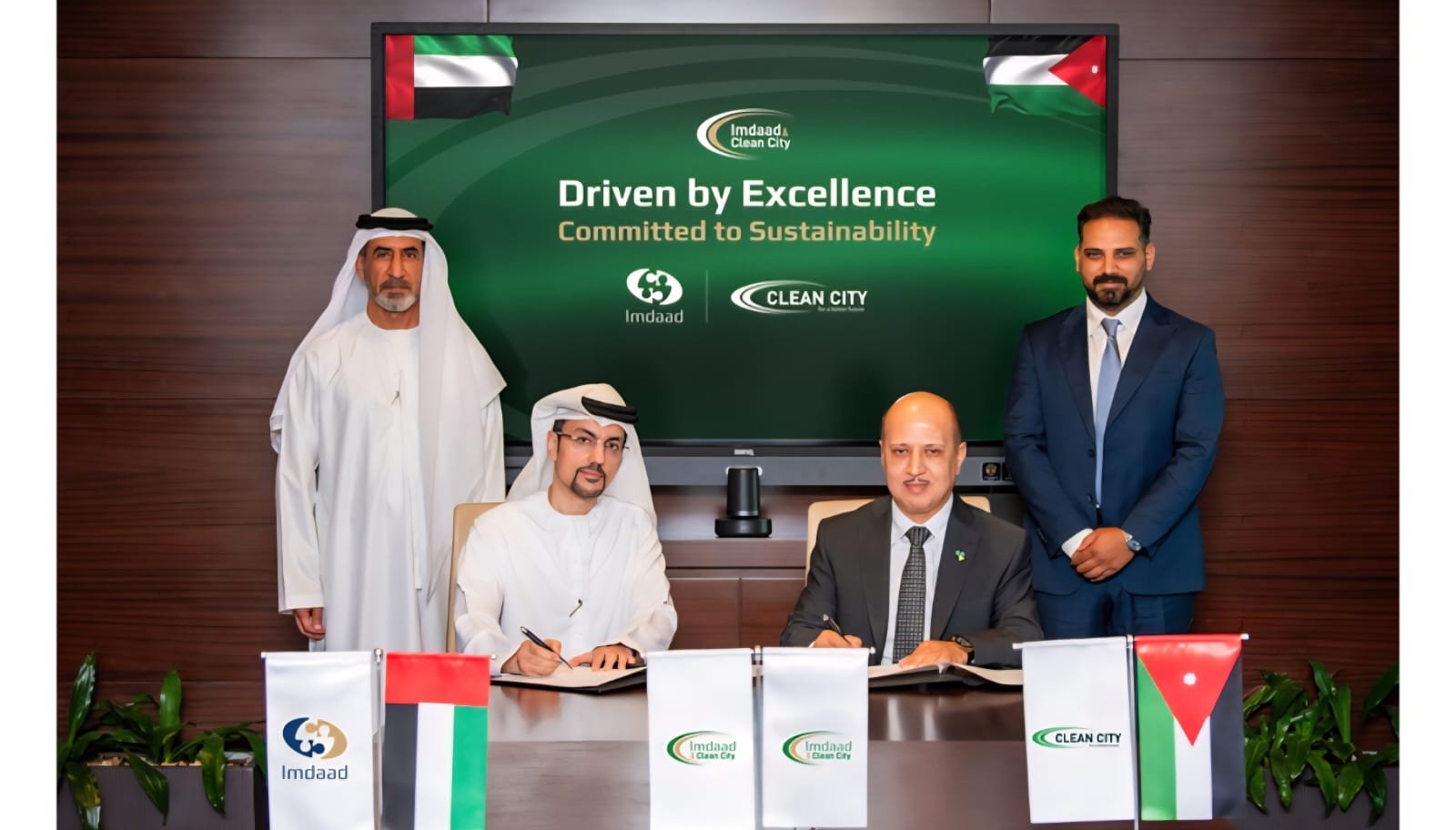 WhatsApp Image 2026-08-08 at 81106 PM1 - عروبة الاخباري | Oroba News Four men in traditional and business attire sign documents at a formal signing ceremony, with UAE flags and a green backdrop that reads 'Driven by Excellence: Committed to Sustainability.'