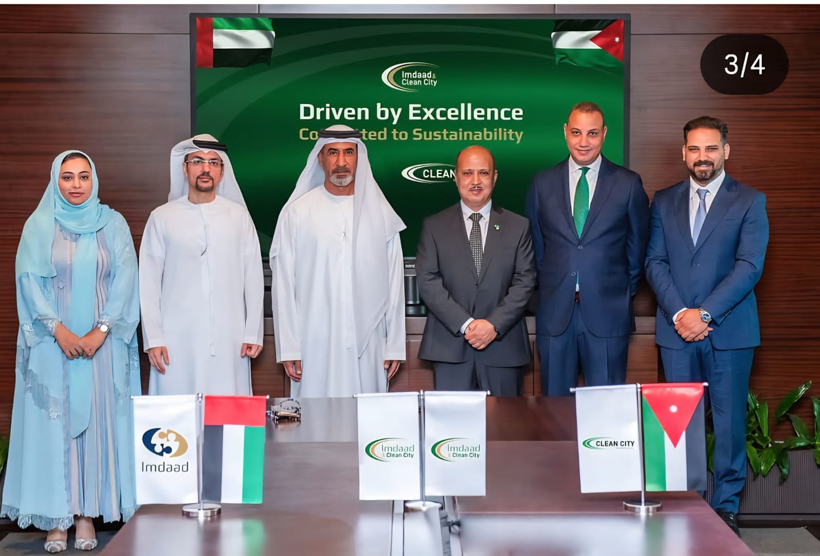 WhatsApp Image 2026-08-08 at 81106 PM2 - عروبة الاخباري | Oroba News Six professionals pose in a conference room behind a table with UAE and Jordan flags; green backdrop reads 'Driven by Excellence'.