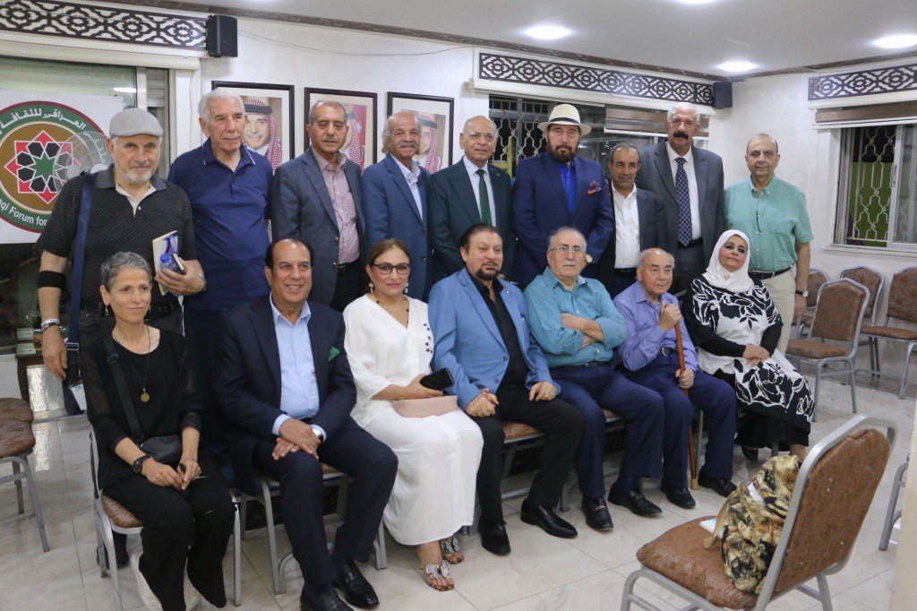 WhatsApp Image 2026-08-10 at 10930 PM - عروبة الاخباري | Oroba News Group of casually/formally dressed people posing for a photo in a meeting room with framed portraits and a decorative banner on the wall behind them.