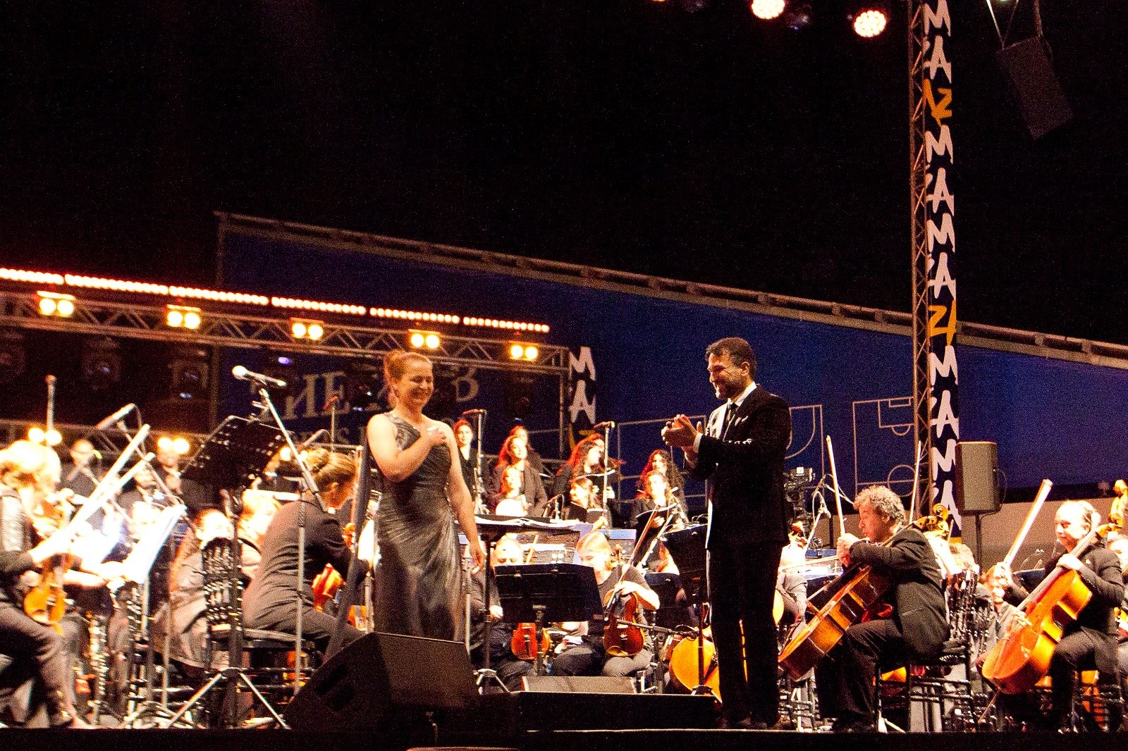 WhatsApp Image 2026-08-10 at 45555 PM 4 - عروبة الاخباري | Oroba News Orchestra performing on stage with a female singer and conductor during a nighttime concert.