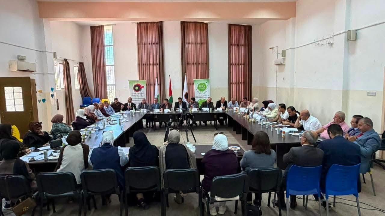 WhatsApp Image 2026-08-16 at 115829 PM - عروبة الاخباري | Oroba News A large meeting in a hall with about 30 people seated around U-shaped tables, with green banners and flags at the far end.