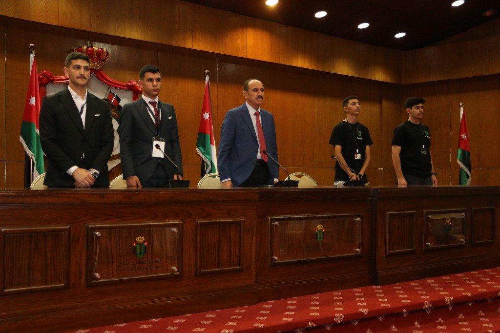 WhatsApp Image 2026-08-23 at 120308 AM1 - عروبة الاخباري | Oroba News Six men stand behind a long wooden dais in a formal government chamber with Jordan flags in the background.
