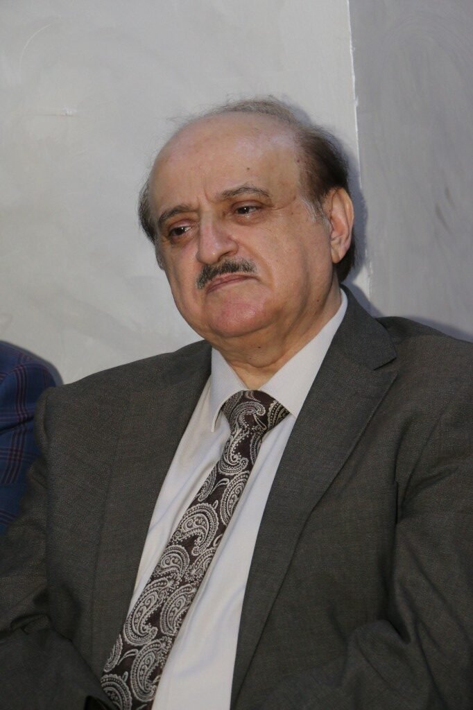 WhatsApp Image 2026-08-25 at 94610 PM1 - عروبة الاخباري | Oroba News Older man with a gray suit and paisley tie sits against a light wall, looking thoughtful.