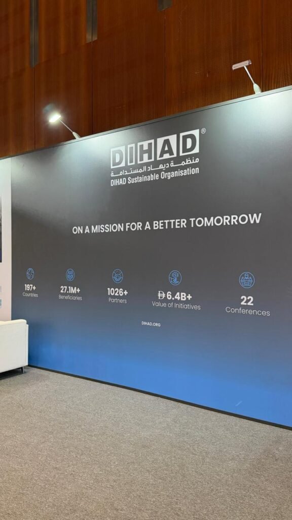 DIHAD exhibition wall with logo, motto 'On a mission for a better tomorrow' and key stats icons for countries, beneficiaries, partners, value, and conferences.