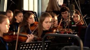 WhatsApp Image 2026-08-29 at 123201 PM 5 - عروبة الاخباري | Oroba News Group of young violinists in an orchestra, focused on their sheet music during a performance.