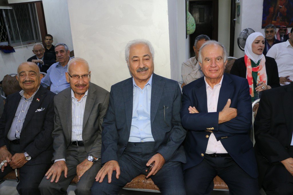 WhatsApp Image 2026-08-31 at 122501 AM - عروبة الاخباري | Oroba News Group of older men in suits sitting closely together at an outdoor social gathering, smiling for the camera.