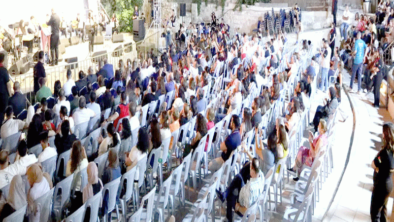 file3 - عروبة الاخباري | Oroba News Large outdoor audience seated in rows watching a live concert on stage .