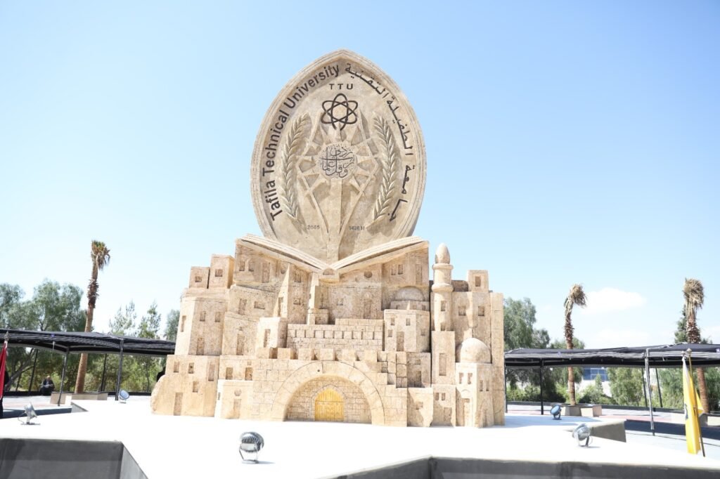 nLR1fd7M0Rq2LslQsSGfagS26ClyA7EyAUhaF0u4 - عروبة الاخباري | Oroba News Large stone monument with an oval plaque featuring an atom symbol and Arabic script, set on a stack of carved book-like blocks against a clear blue sky.